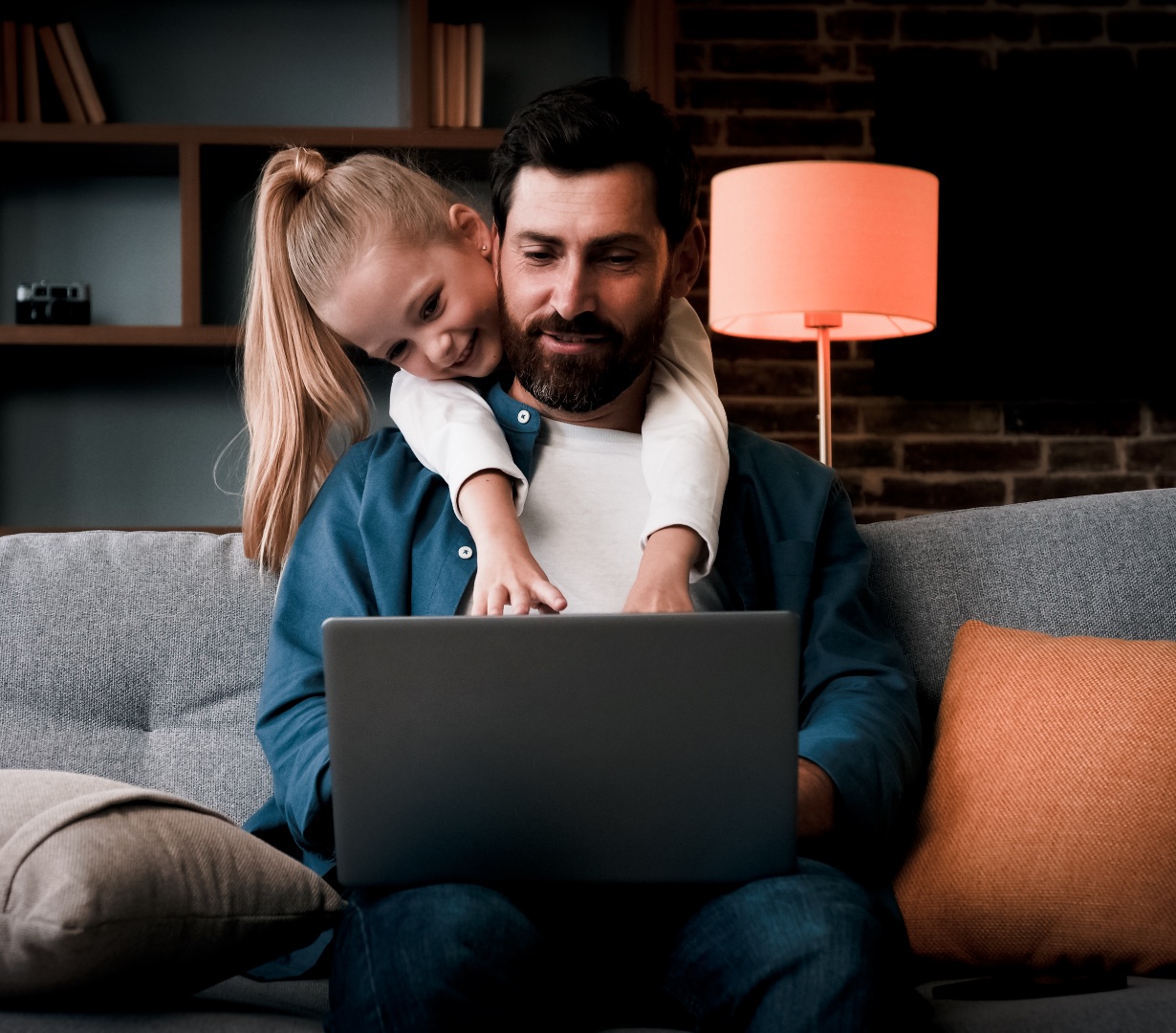 A parent managing the day on a laptop with their child close by