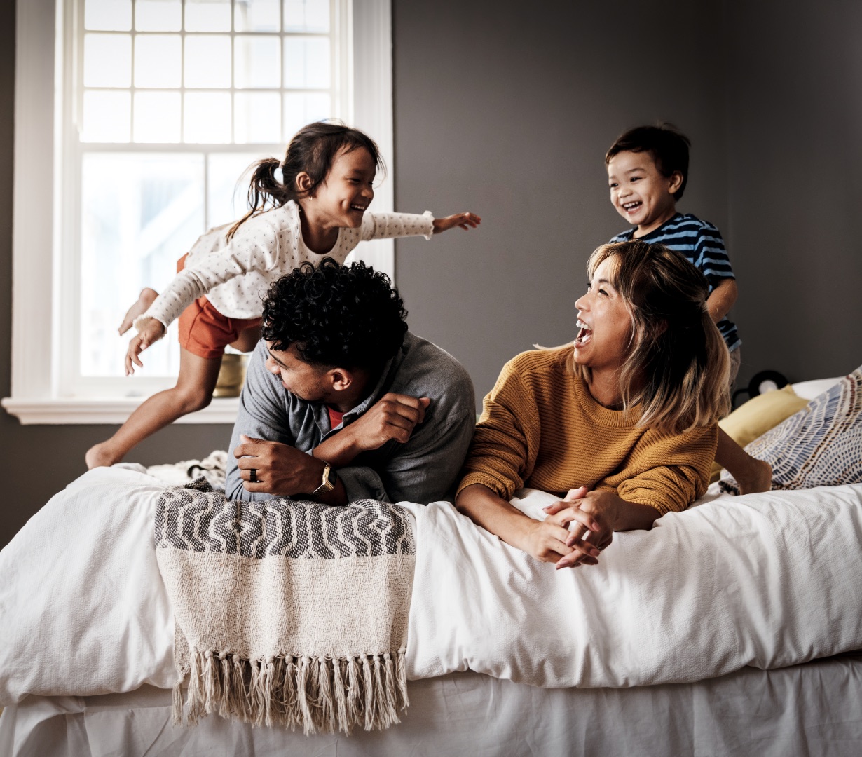 A whole family playing together on a bed at home