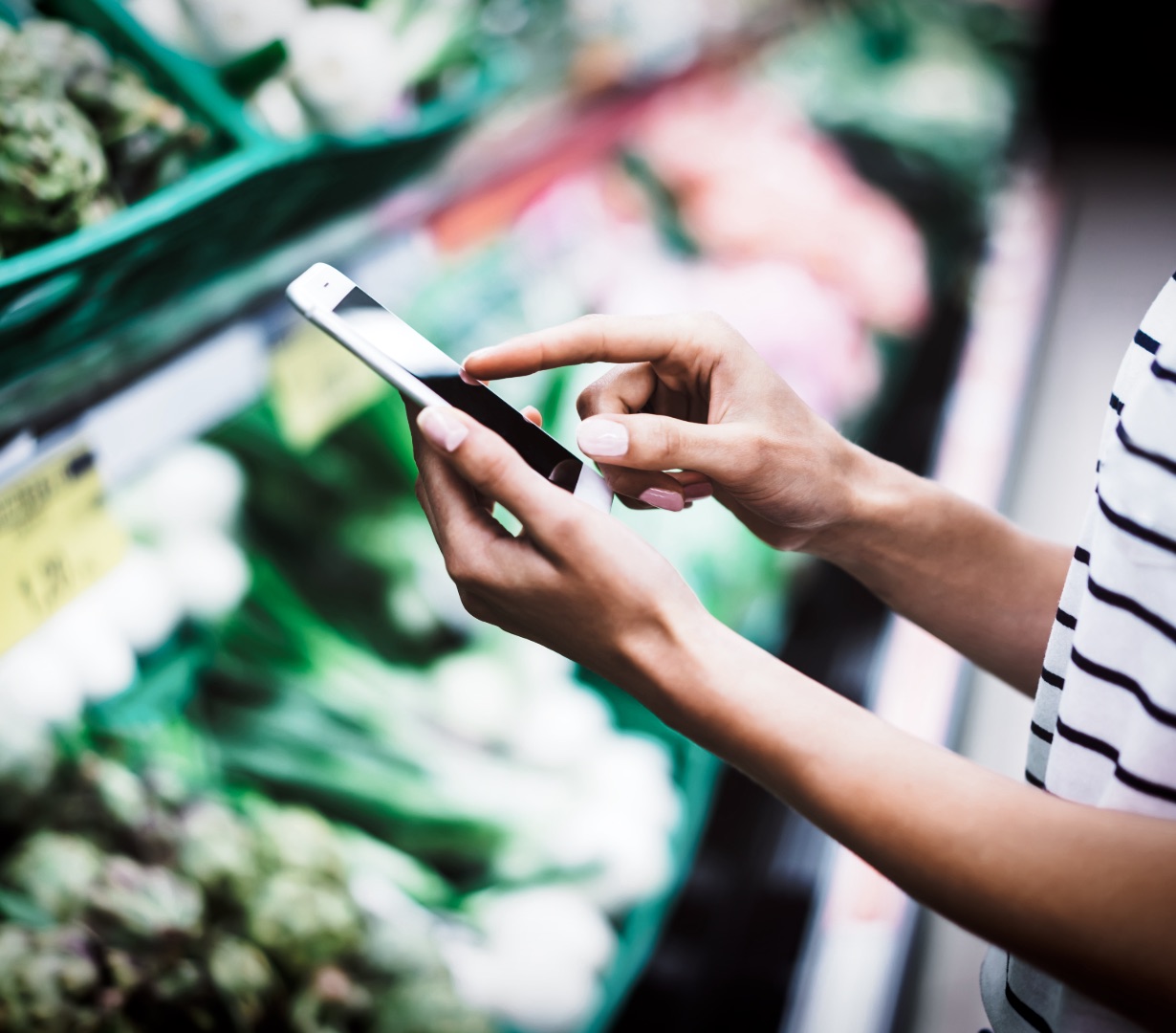 A person checking prices and budget on their phone while shopping